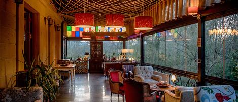 A cozy interior with a wooden ceiling, large windows, and comfortable seating.