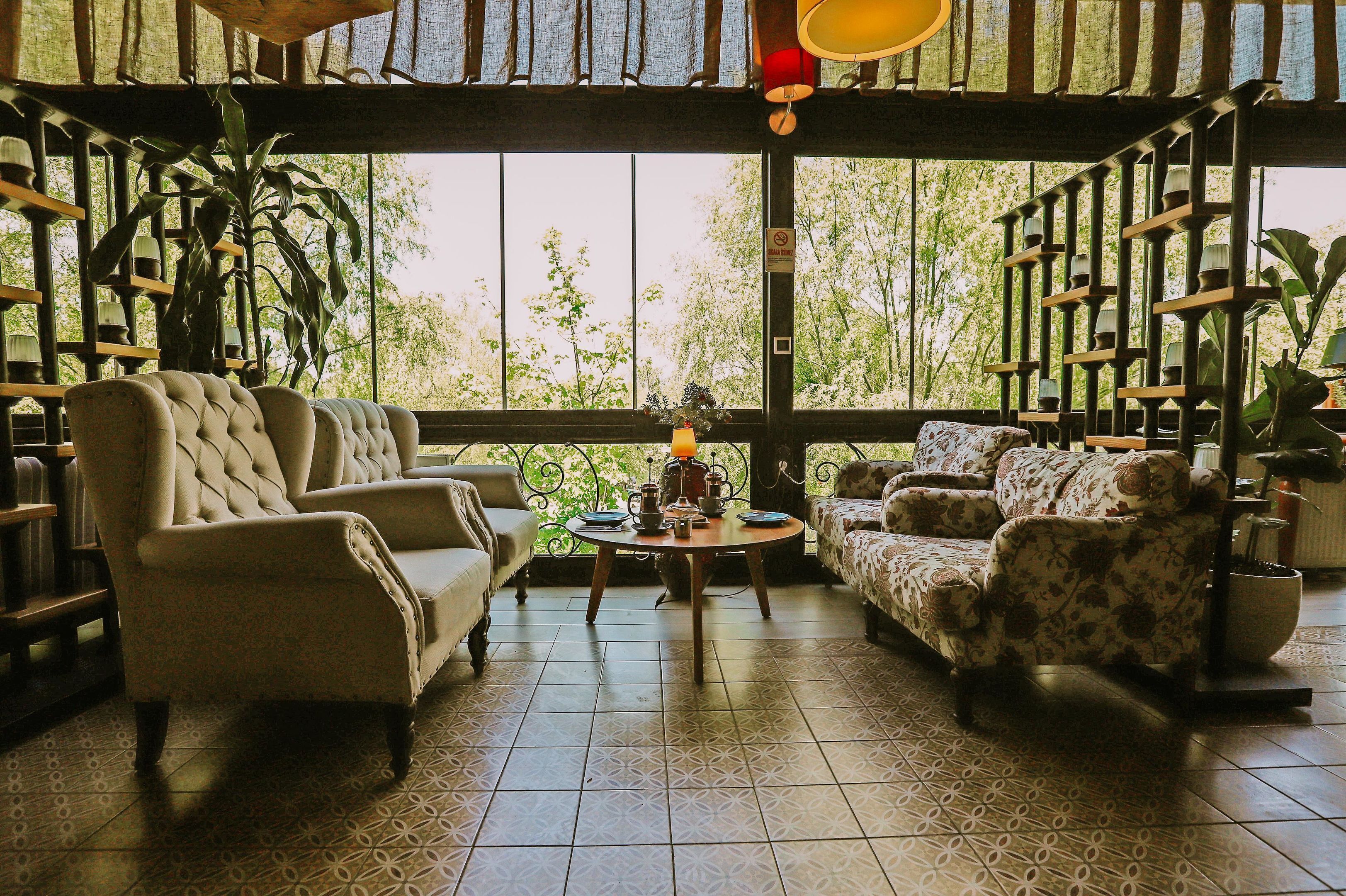 A cozy room with a large window, two sofas, a coffee table, and a bookshelf.