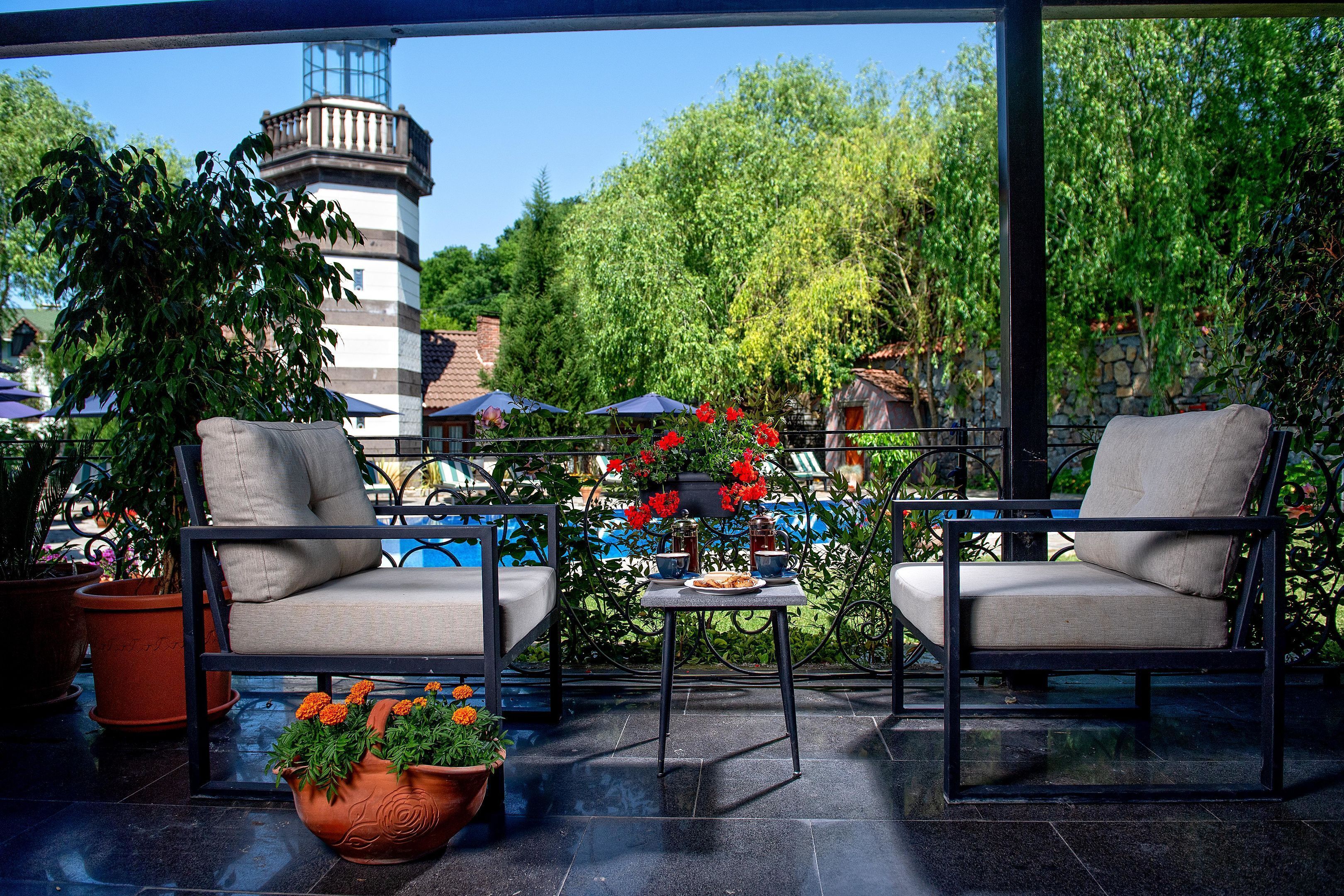 An outdoor seating area with two chairs, a table, and potted plants.