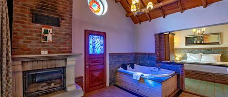 A room with a fireplace, a large bathtub, and a wooden ceiling.