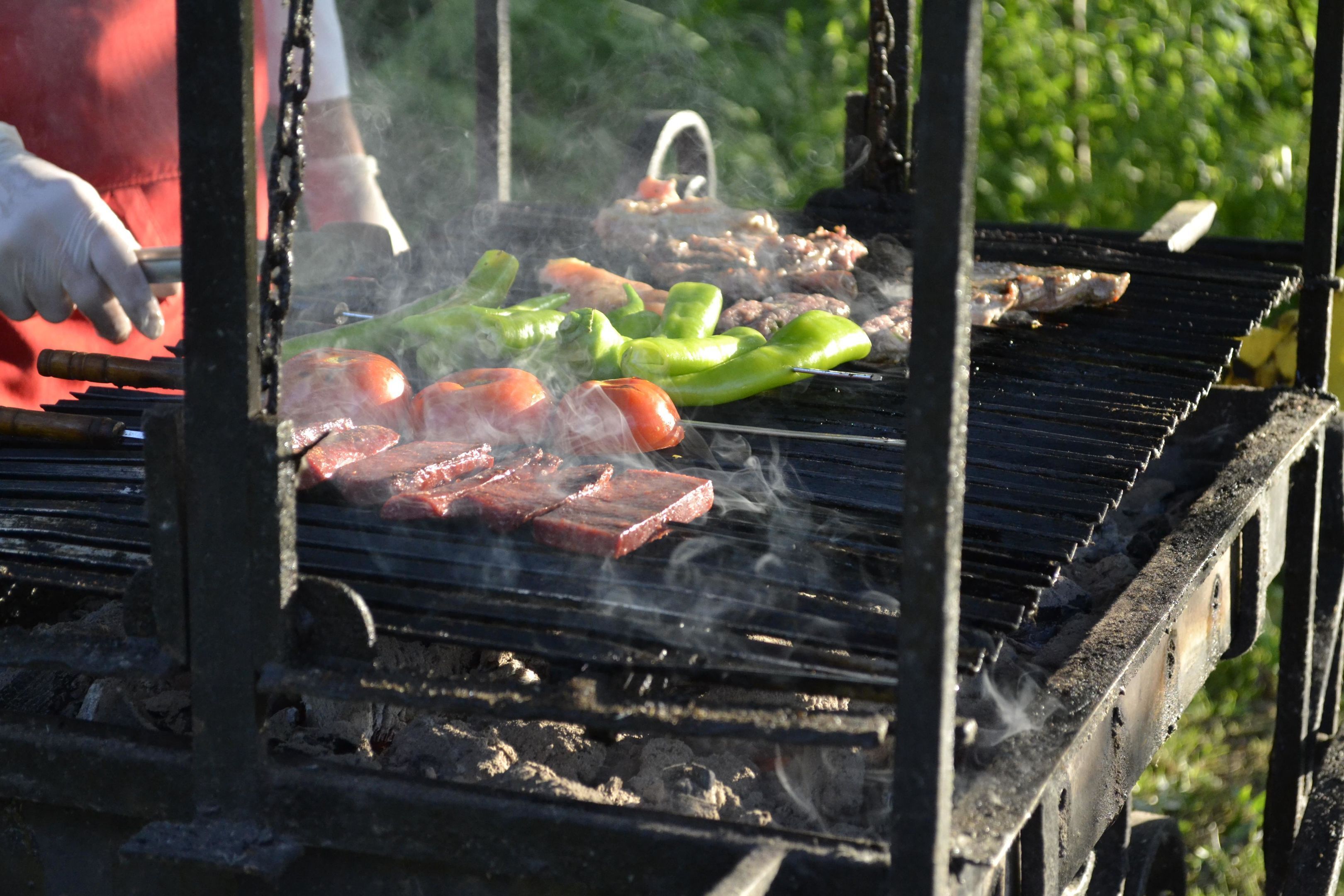 Una parrilla con diversos tipos de carne y verduras asándose.