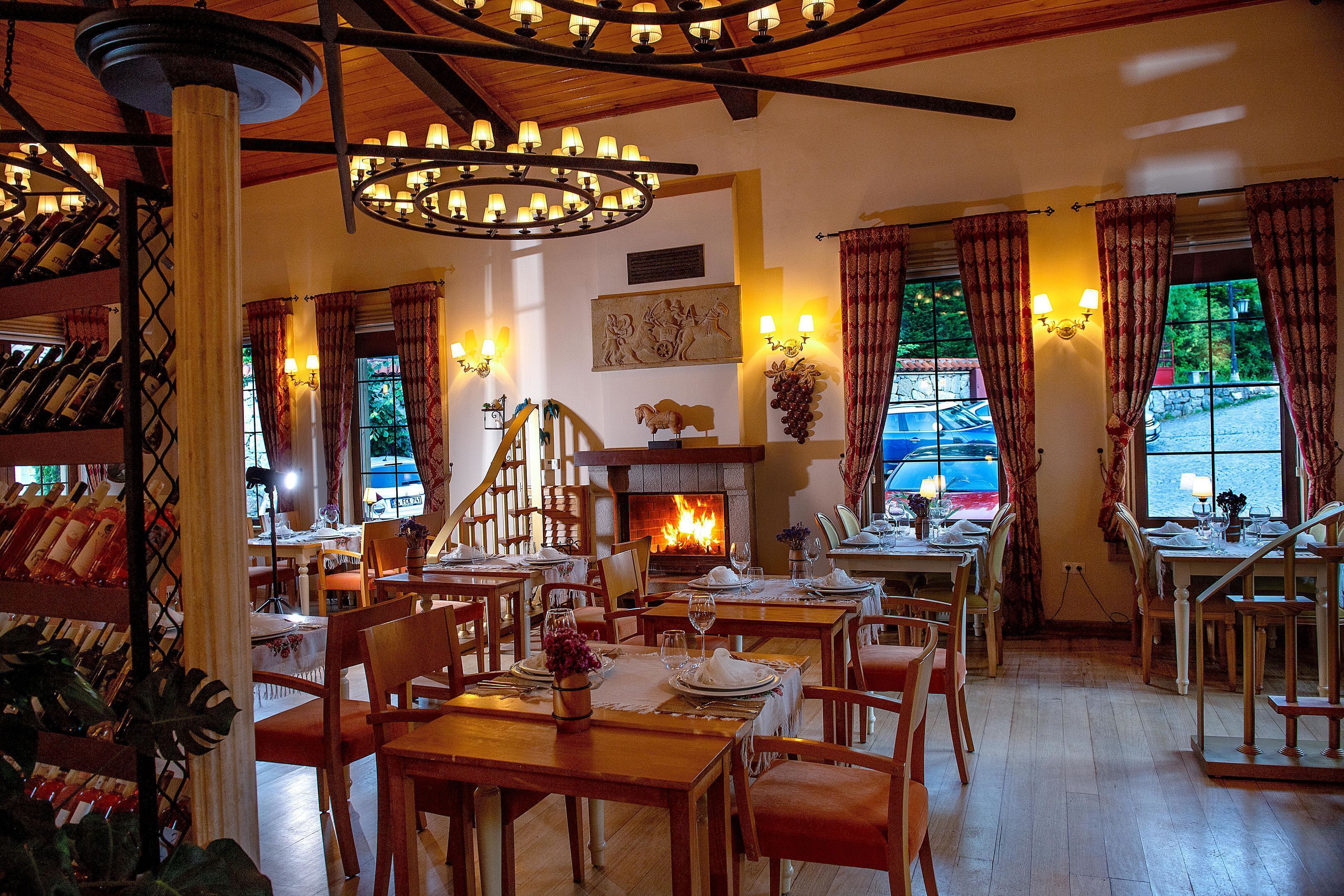Un restaurante con mesas y sillas de madera, una chimenea y vistas al exterior.