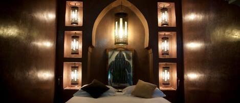 Habitación de hotel con una cama grande, un candelabro y apliques de pared.