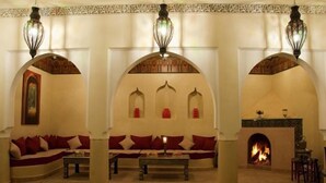 A traditional interior with a sofa set, a fireplace, and decorative arches. - Riad Granvilier (Marrakech)