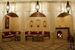 Un interior tradicional con un conjunto de sofás, una chimenea y arcos decorativos.
