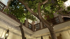A multi-level interior with ornate railings and a tree in the center. - Riad Granvilier (Marrakech)