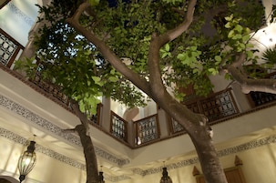 Un interno a più livelli con ringhiere decorate e un albero al centro.