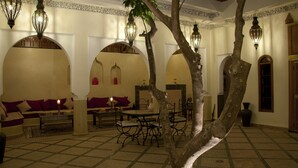 A traditional Moroccan interior with arches, a central dining area, and hanging lanterns. - Riad Granvilier (Marrakech)