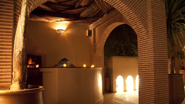 A courtyard with a reception area, brick arches, and a fire feature. - Riad Granvilier (Marrakech)