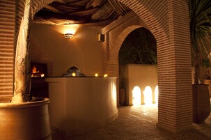 Un patio con zona de recepción, arcos de ladrillo y un hogar.