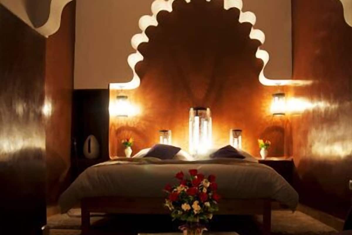 A bedroom with a large bed, a decorative wall arch, and two bedside lamps.
