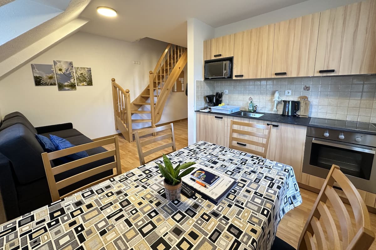 A compact living space with a dining area, kitchenette, and a staircase.