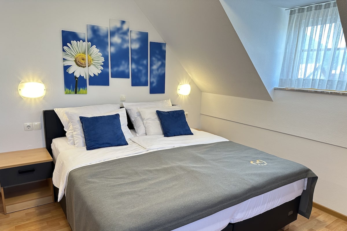 A bedroom with a bed, bedside tables, and wall art.