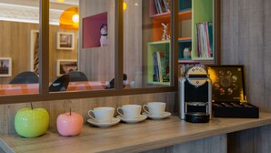 A coffee station with a Nespresso machine, cups, and decorative apples. - Reims Hotel (Paris)