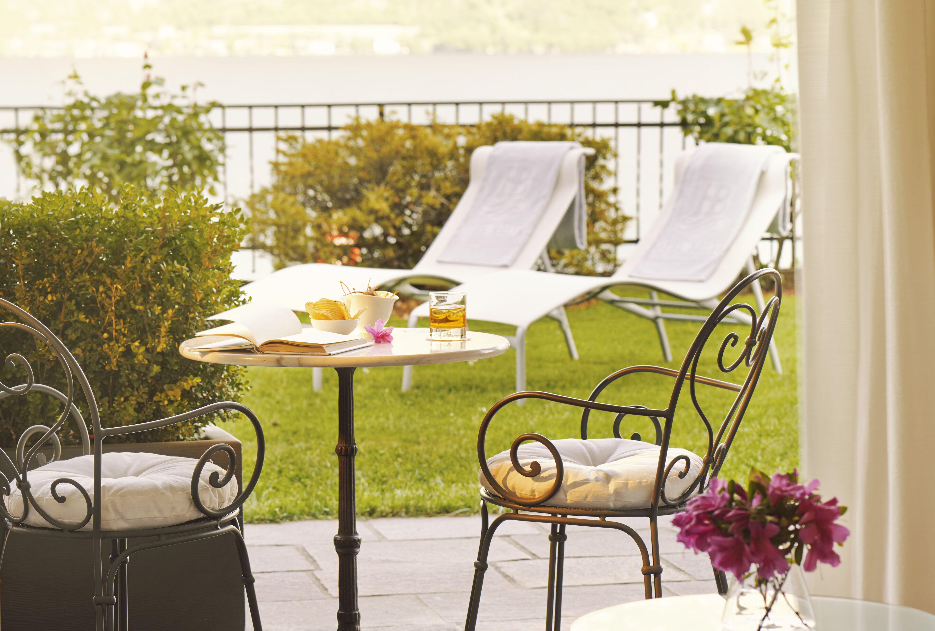 A patio with a table set for two, surrounded by lounge chairs.