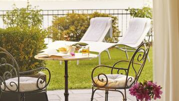 A patio with a table set for two, surrounded by lounge chairs.