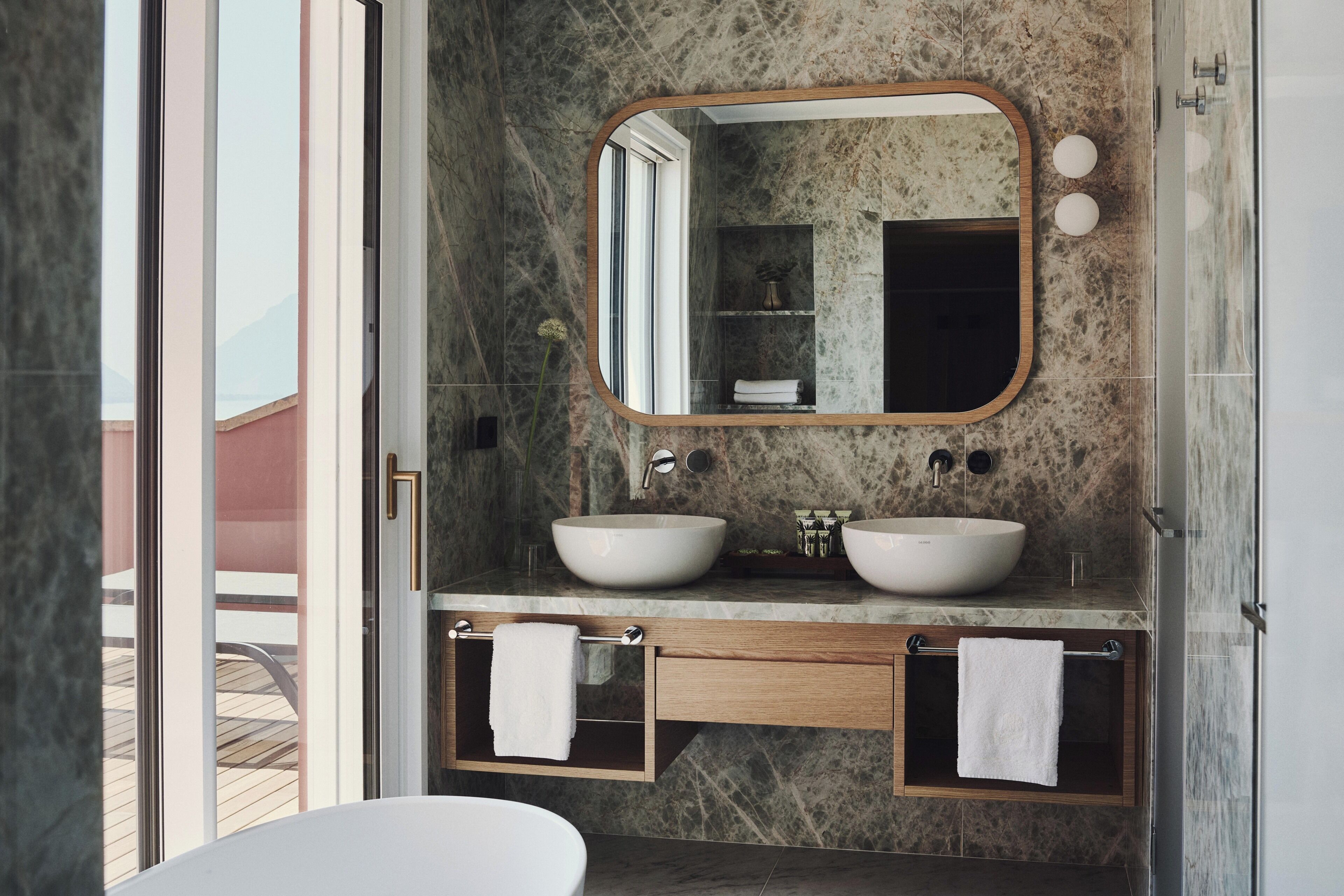 Un bagno con due lavandini, uno specchio grande e una vasca da bagno.