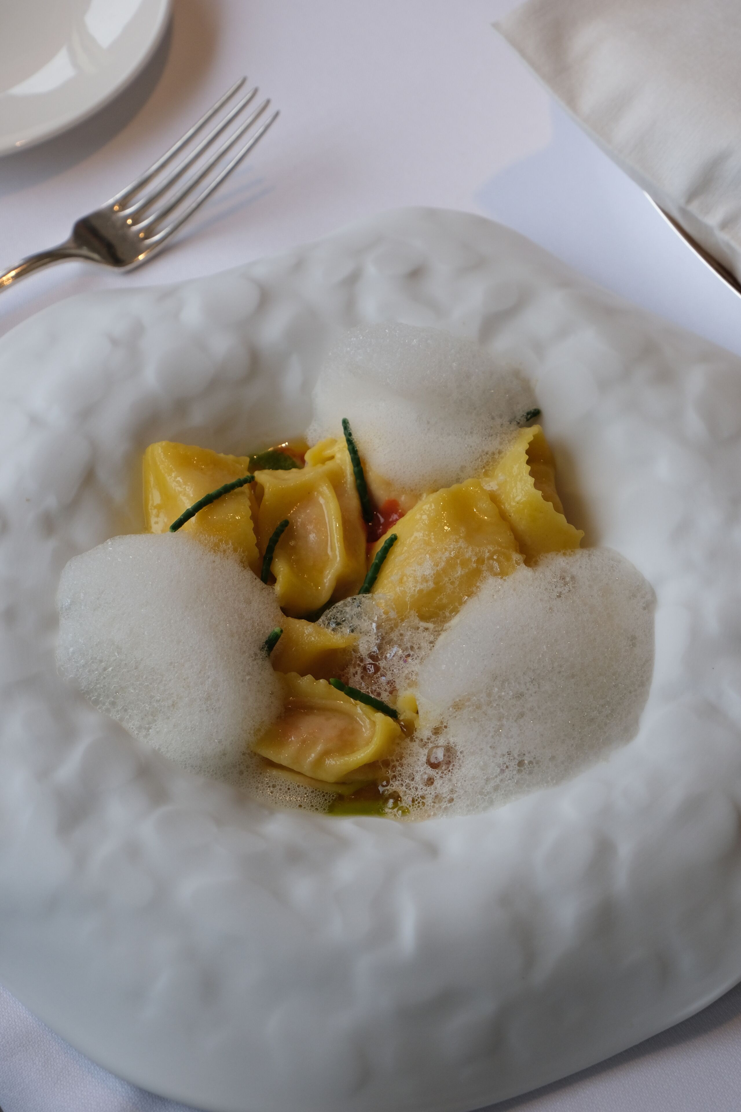 A white plate with a dessert consisting of yellow fruit pieces and sugar.
