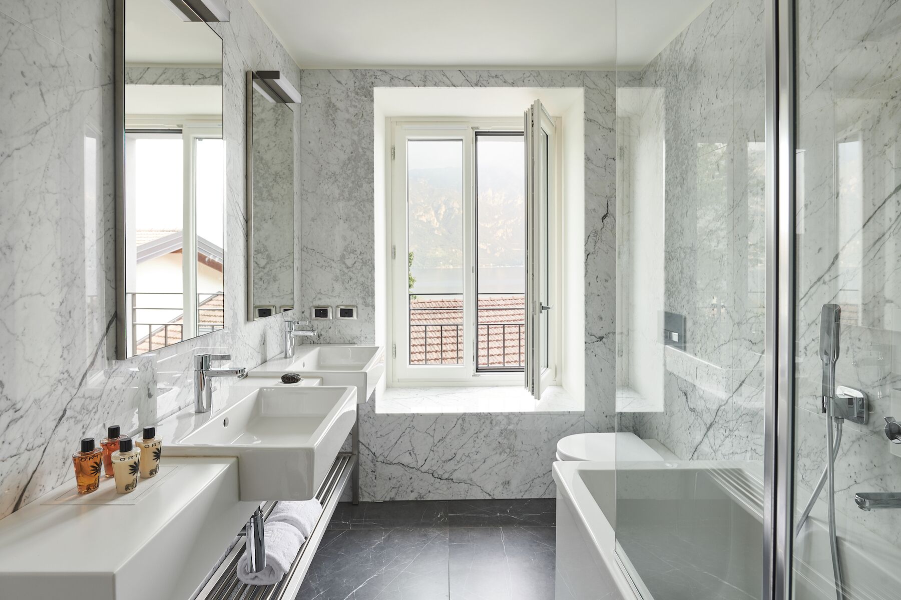 Ein modernes Badezimmer mit einem großen Spiegel, zwei Waschbecken, einer Badewanne und einer Dusche.
