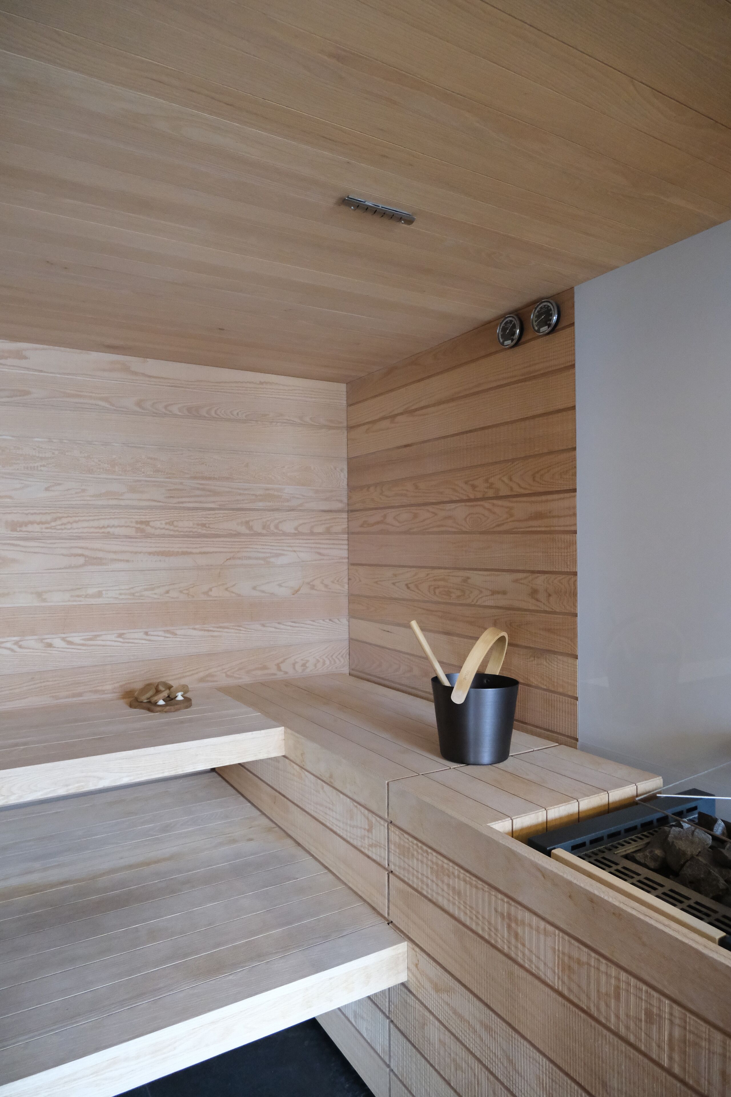 Una cocina moderna con armarios de madera, estufa empotrada y un cubo de basura negro con una cuchara de madera.