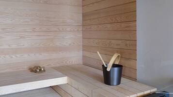 Una cocina moderna con armarios de madera, estufa empotrada y un cubo de basura negro con una cuchara de madera.