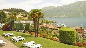 A view of a lakeside property with lounge chairs, a pool, and a mountain backdrop. - Hotel Belvedere (Bellagio)