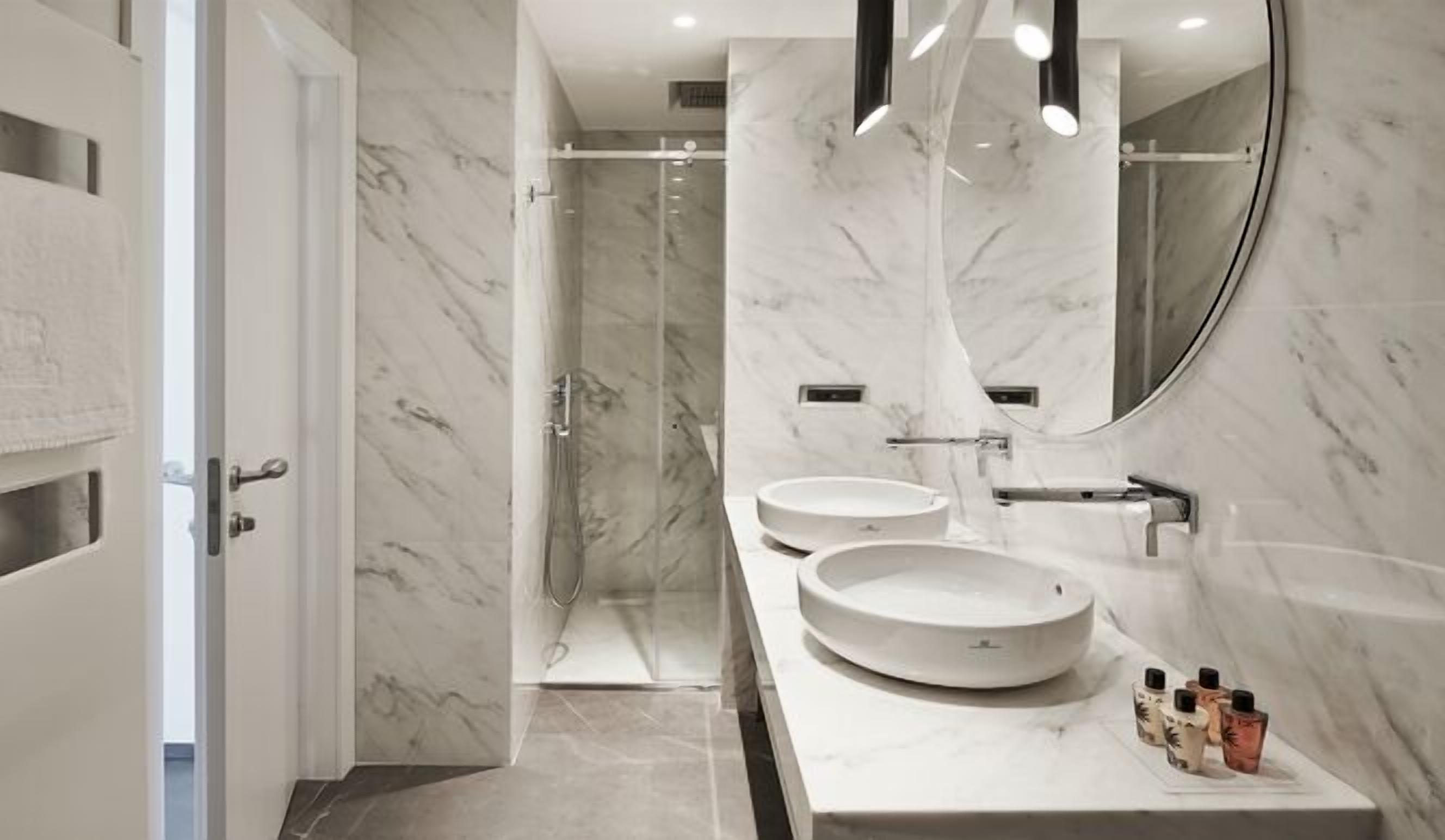 Un baño moderno con dos lavamanos redondos, un espejo grande y una zona de ducha.