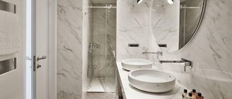 A modern bathroom with two round sinks, a large mirror, and a shower area.