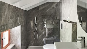 A modern bathroom with a bathtub, toilet, and sink, featuring marble walls and a large mirror.
