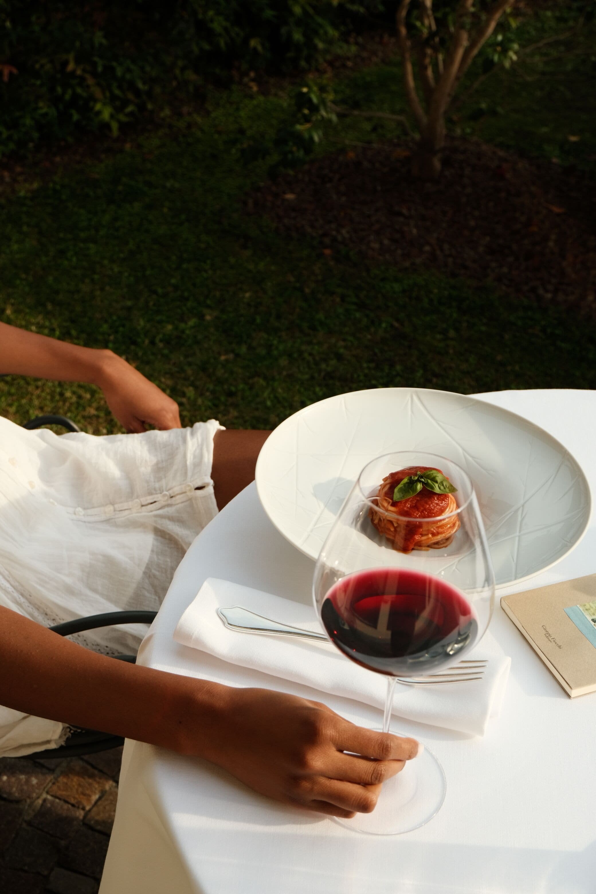 A dining table with a plate of food, a glass of red wine, and a menu.