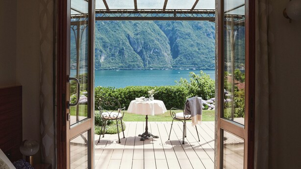 A bedroom with a large window overlooking a scenic lake and mountains. - Hotel Belvedere (Bellagio)