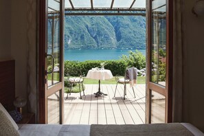 A bedroom with a large window overlooking a scenic lake and mountains.