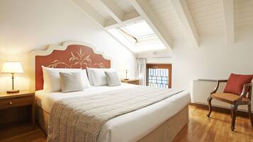 Un dormitorio con una cama grande, una mesita de noche, una silla, un tragaluz y una ventana.