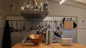 Una cocina con una mesa de madera, un colgador para ollas y diferentes utensilios de cocina.