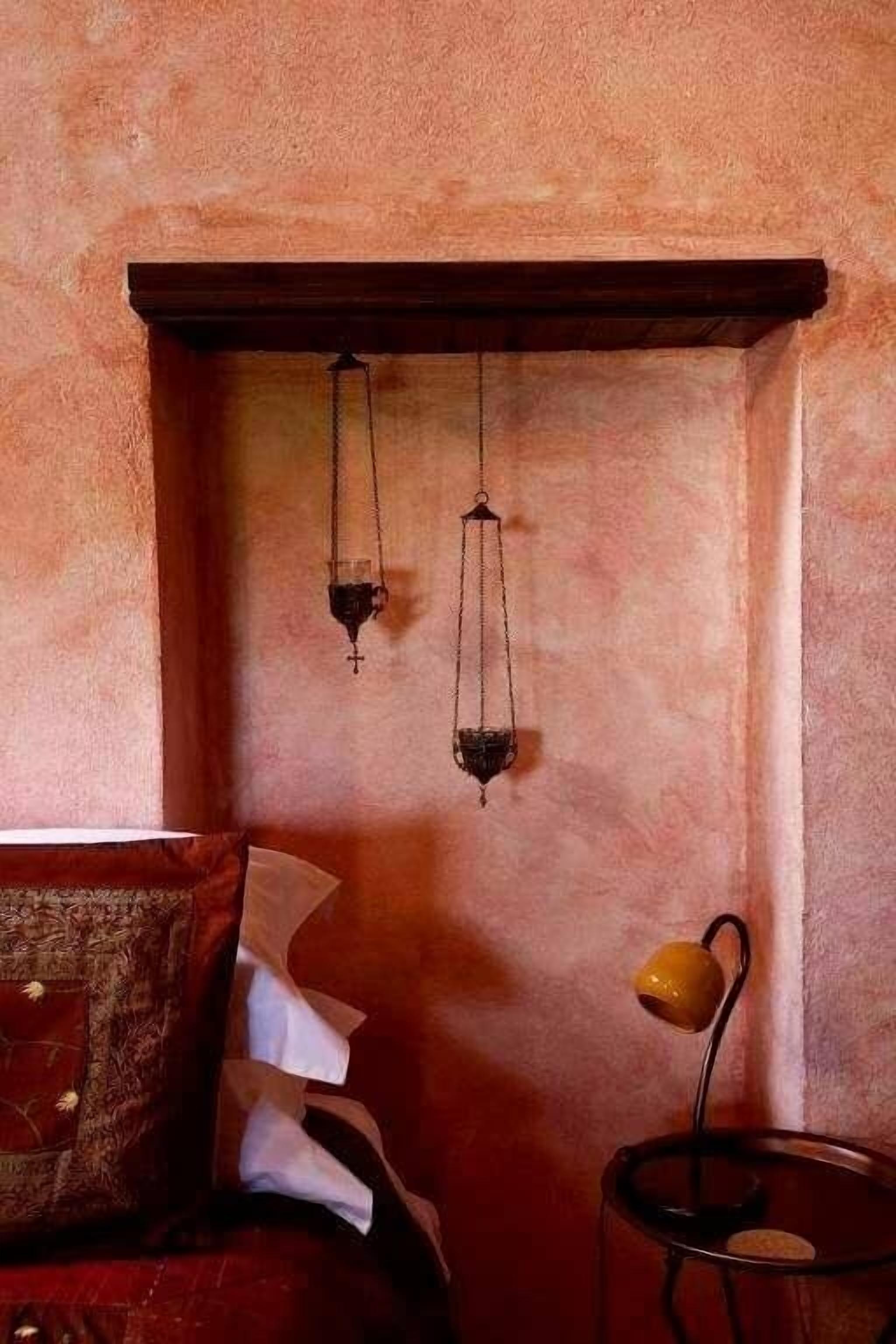 A bedroom with a bed, a bedside table, and a hanging light fixture.