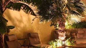 Un espace extérieur paisible, aménagé avec une piscine, des chaises longues et un éclairage d’ambiance.
