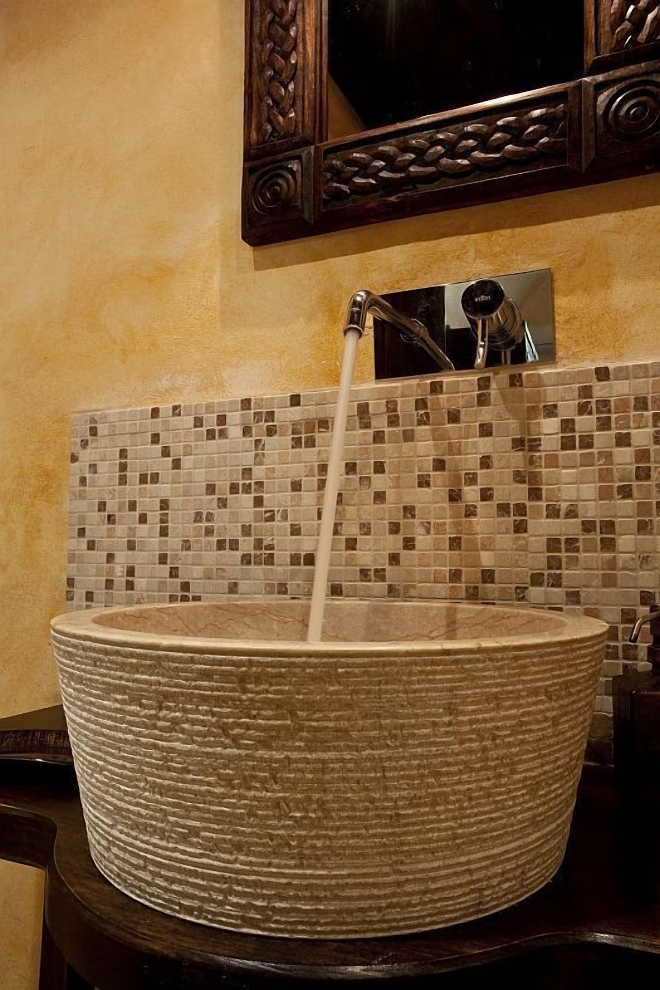 A large, textured basin with a faucet, set against a mosaic tile backsplash.