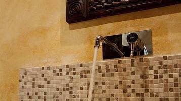 A large, textured basin with a faucet, set against a mosaic tile backsplash.
