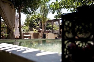 A pool area with a stone structure, potted plants, and a table.