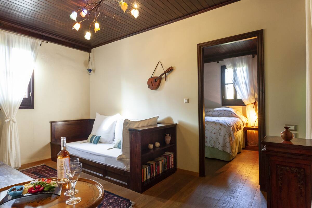 Ein gemütliches Zimmer mit einem Bett, einem Bücherregal, einer Gitarre und einem Essbereich mit einer Platte Essen und Gläsern.