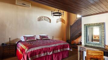 Une chambre à coucher avec un grand lit, une commode en bois, un miroir et un escalier.