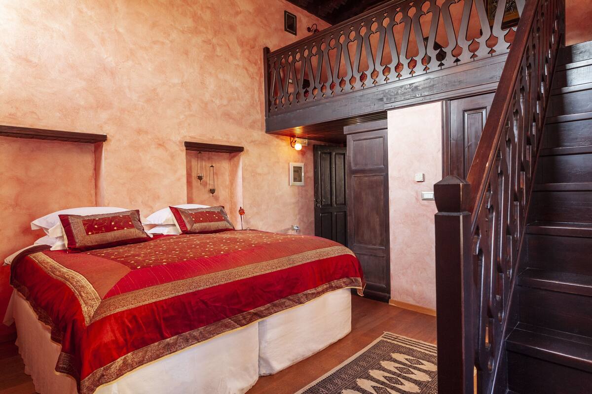 Ein Schlafzimmer mit einem großen Bett, einer Holztreppe und einer dekorativen Decke.