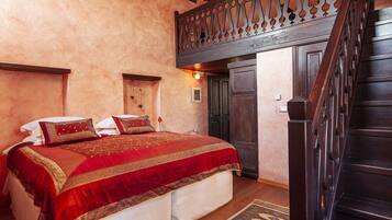 Un dormitorio con una cama grande, una escalera de madera y un techo decorativo.