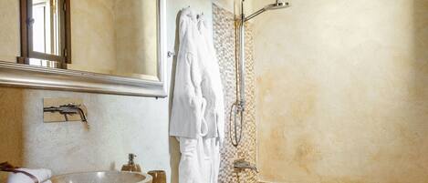 A bathroom with a wooden ceiling, a large mirror, a sink with a beige countertop, a bathtub, and a toilet.