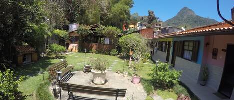 A courtyard with a bench, a small doghouse, and a patio area with a table and chairs.