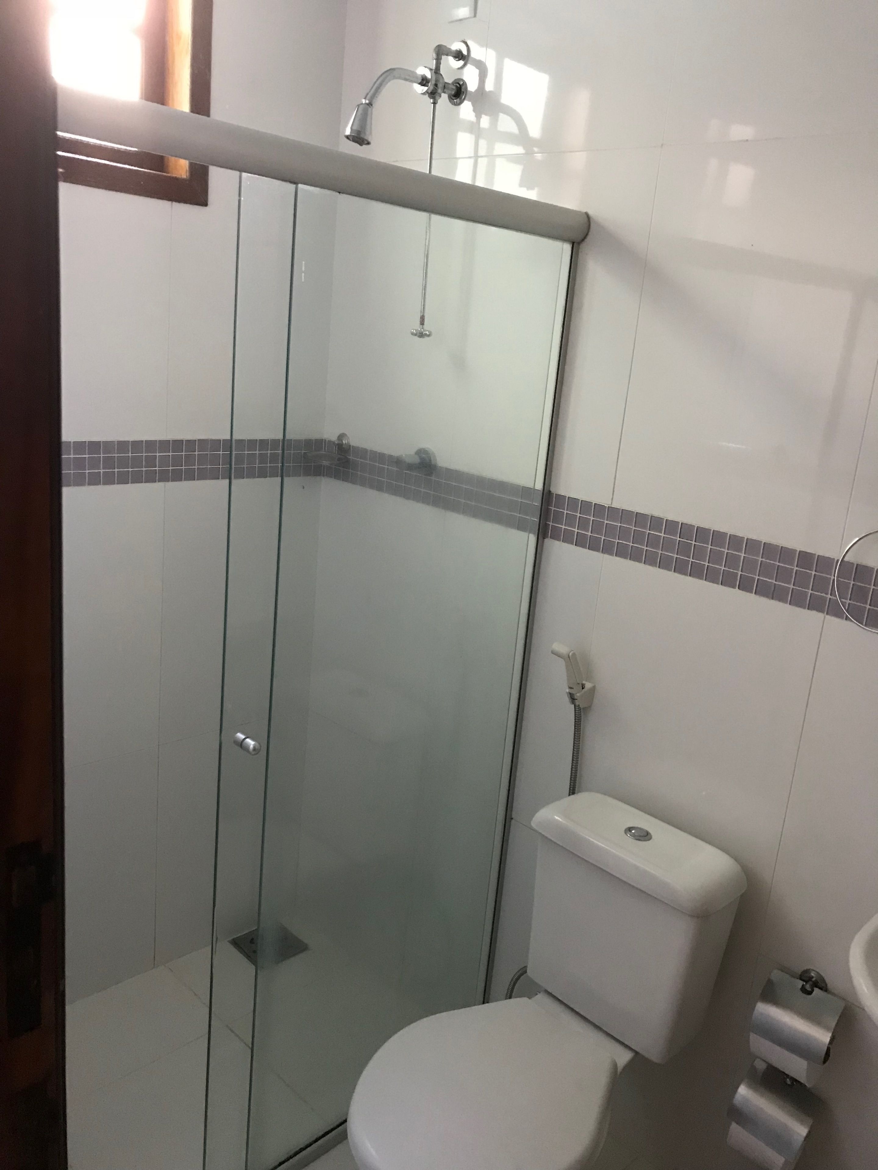 Un baño con ducha envuelta en vidrio, inodoro y lavamanos.