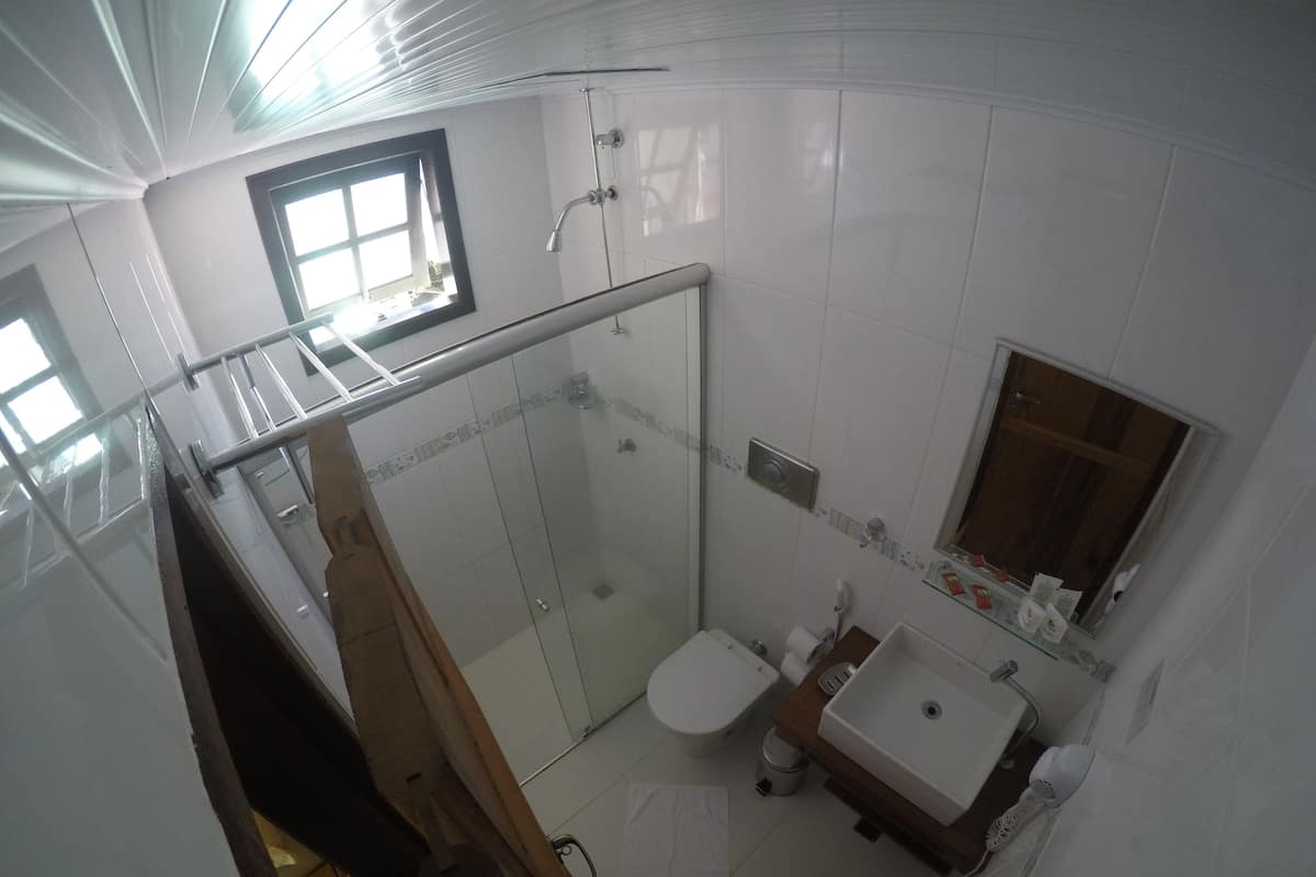 A modern bathroom with a glass-enclosed shower, a toilet, and a sink with a mirror.