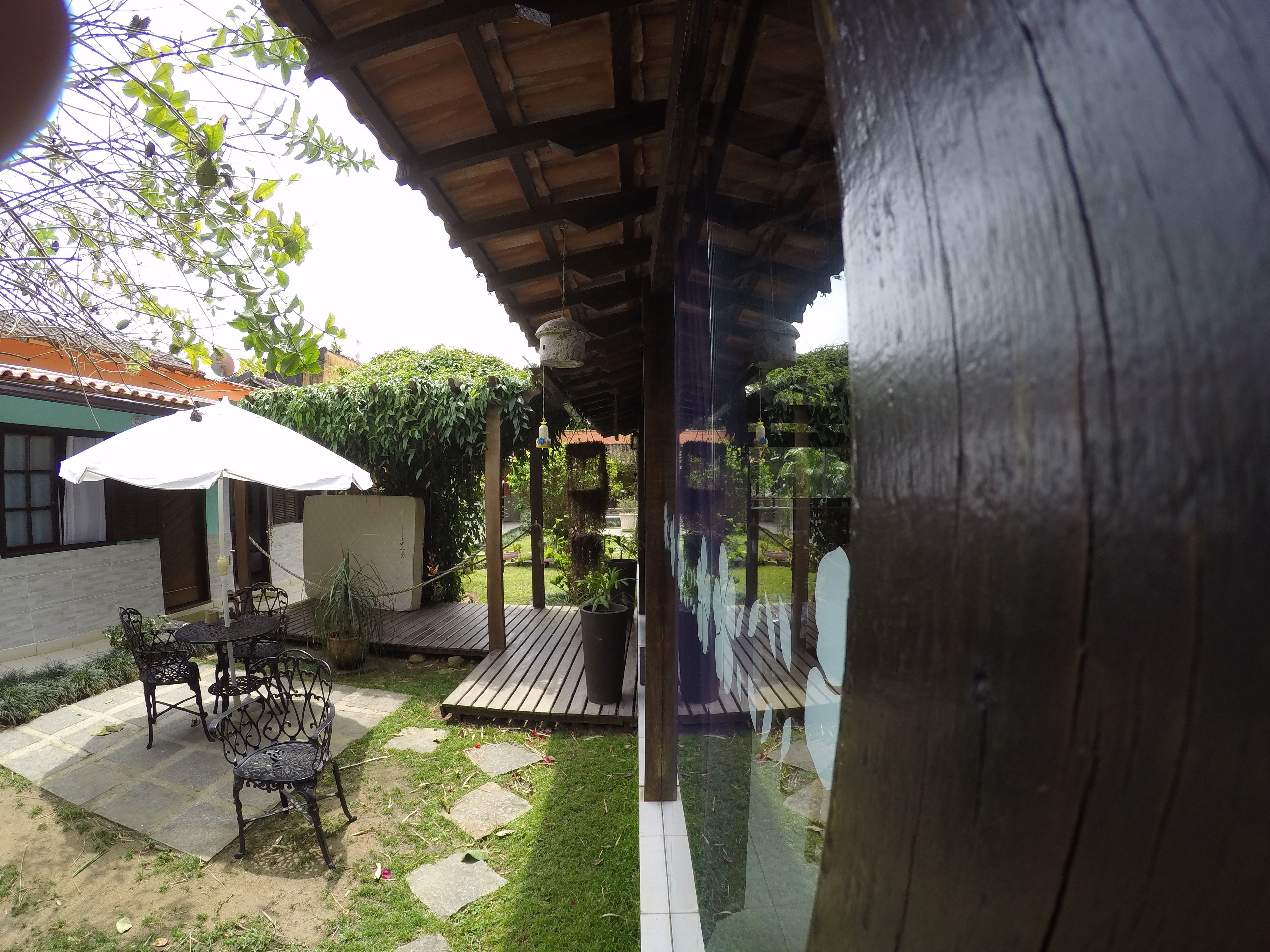 A covered patio area with a wooden deck, outdoor furniture, and a white umbrella.