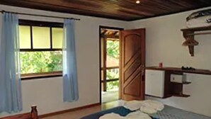 Une chambre à coucher avec un lit, une porte en bois, une fenêtre avec des rideaux et une petite table avec une lampe.
