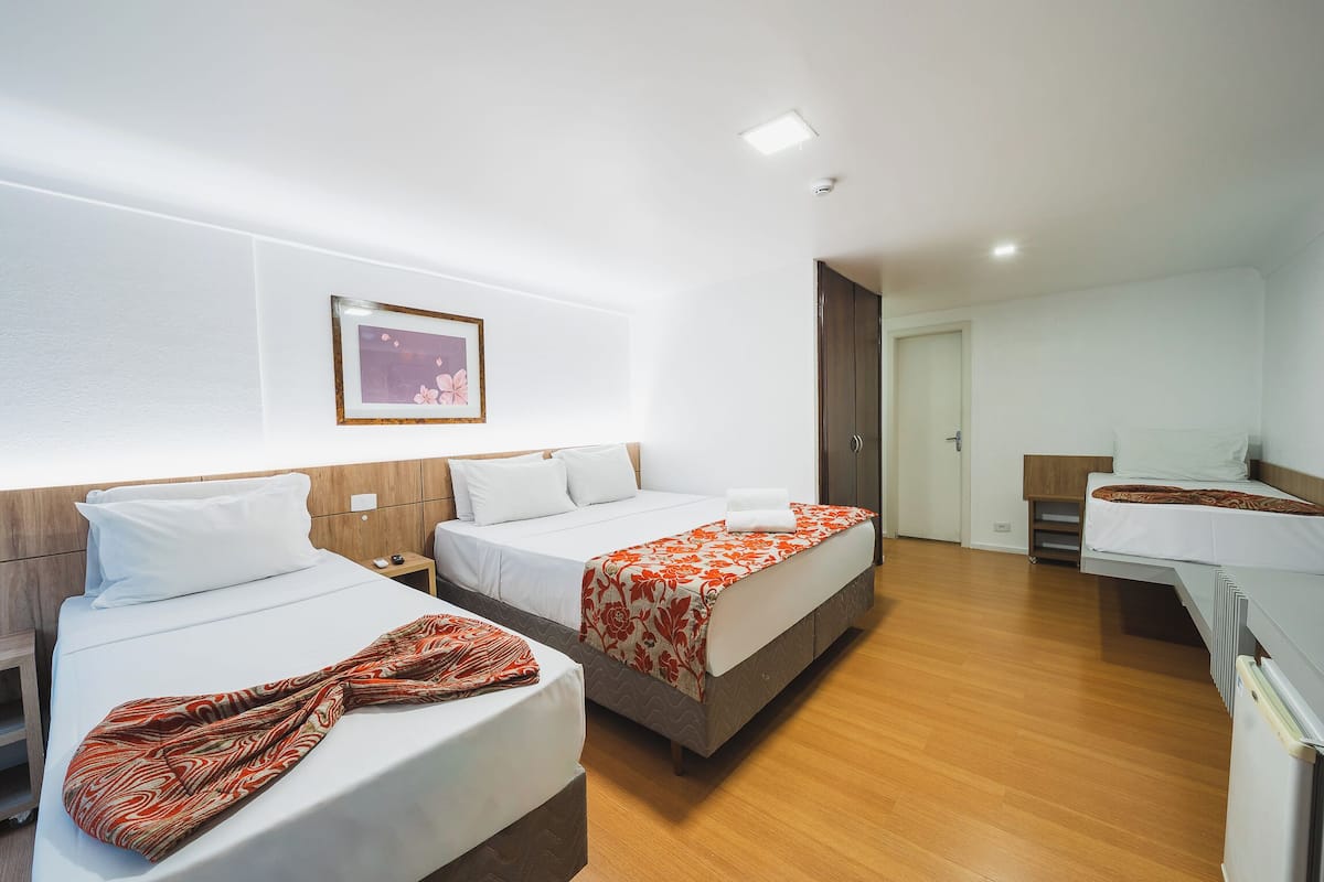 Habitación de hotel con dos camas, cabecera de madera, un cuadro en la pared y un escritorio pequeño con una silla.